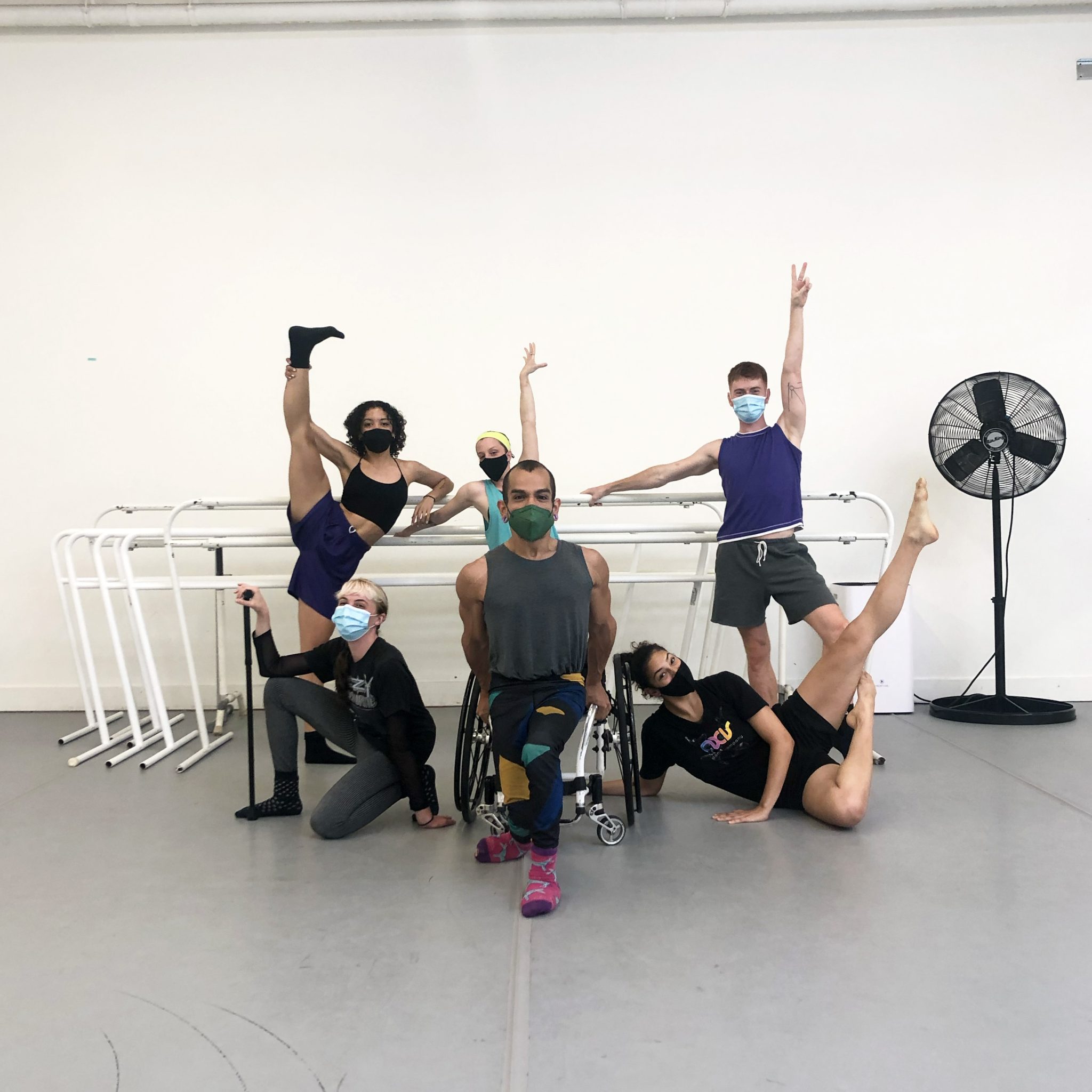 The AXIS Dancers form a tableu: In the center, Janpi lifts themself on their wheelchair, Dawn and Zara pose in their sides with Alaka, Louisa and David in the back.