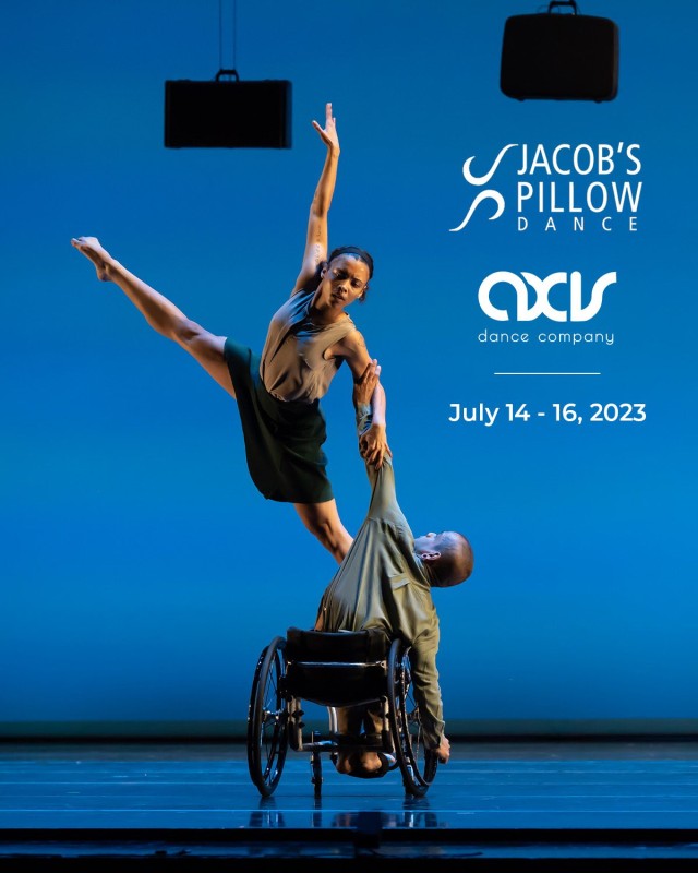 Janpi hold a side lunge in their wheelchair; Alaja places one foot on Janpi's knee and soars through space with their other leg lifted in an upward extension. Luggage hangs from the ceiling above the dancers. White AXIS and Jacob's Pillow logos are placed on the image