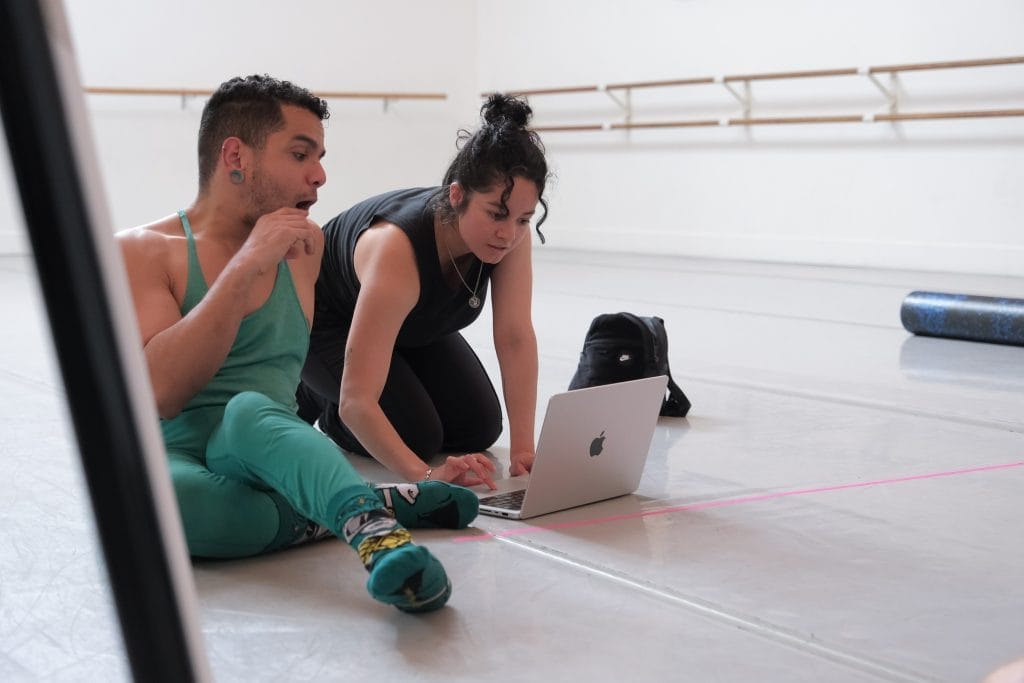 Joelle Santiago looks over rehearsal footage on a laptop with AXIS Dancer JanpiStar