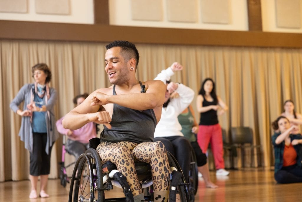 JanpiStar, who is a wheelchair user, teaches salsa class and rolls their arms.